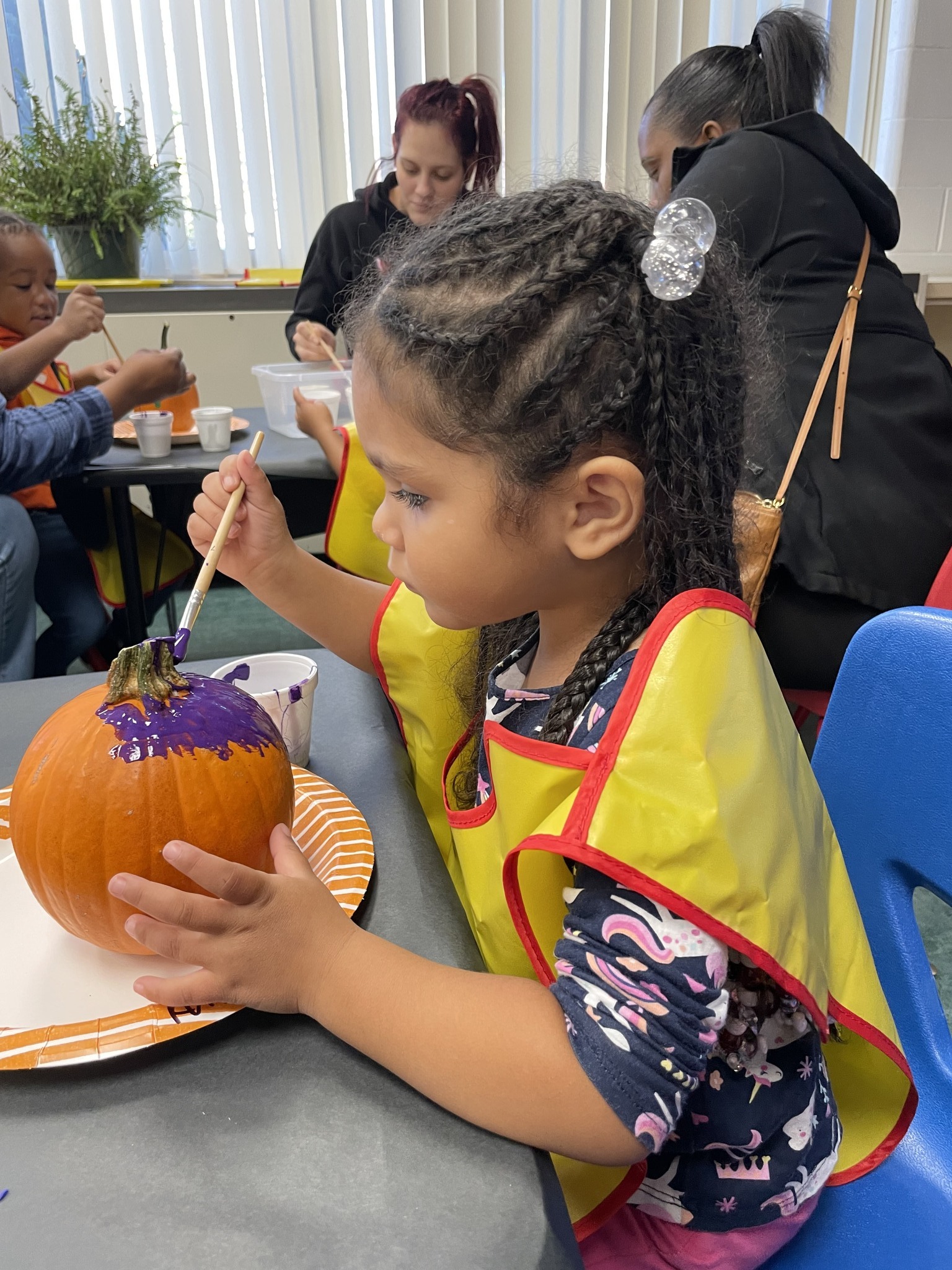Preschool girl paints a pumpkin